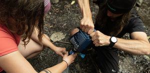 A woman is putting a water bottle on a rock.