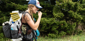 A woman with a backpack in the woods.
