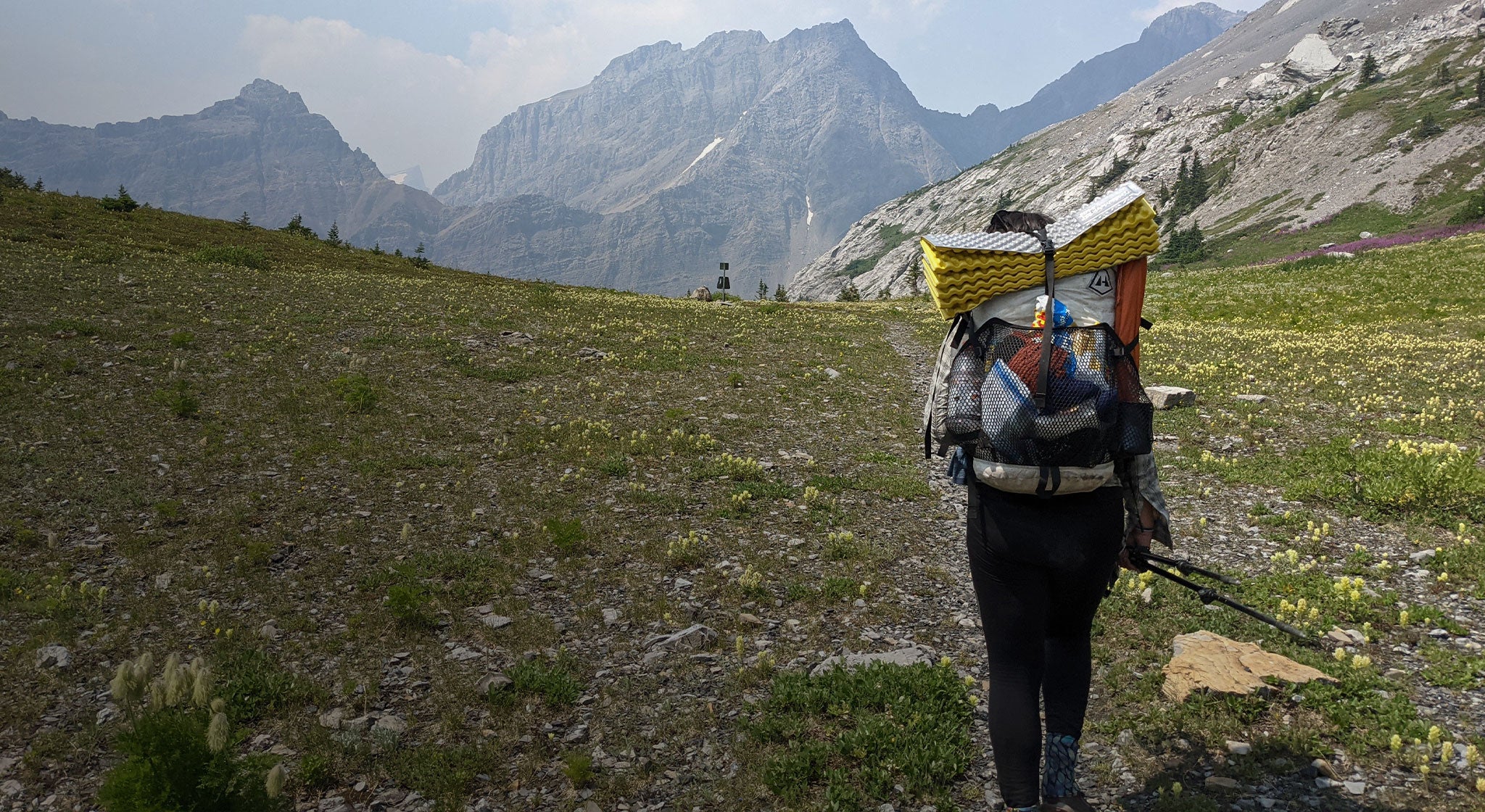 A hiker with a backpack walking through a mountainous area.