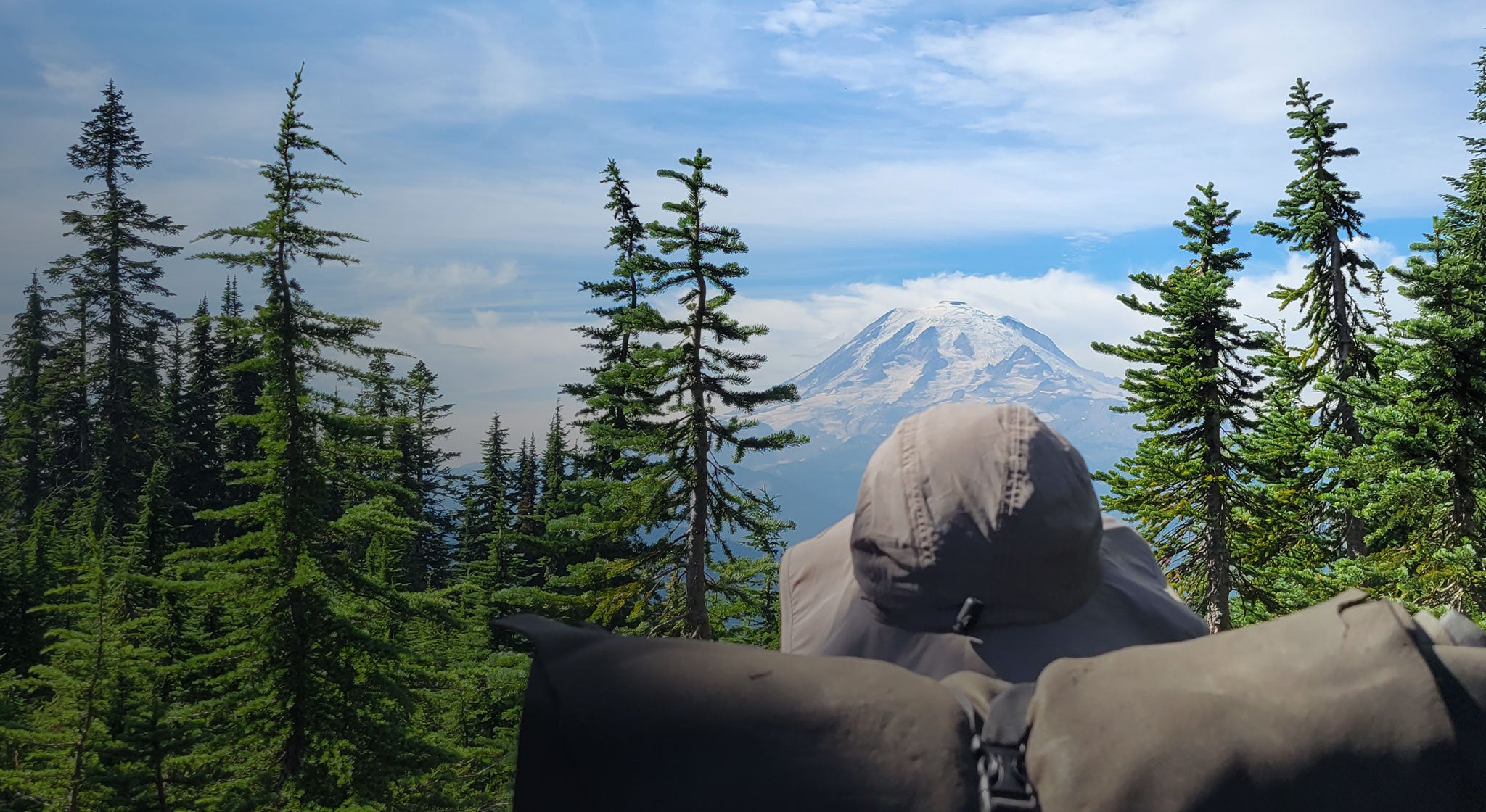 A person with a backpack looking at a mountain.