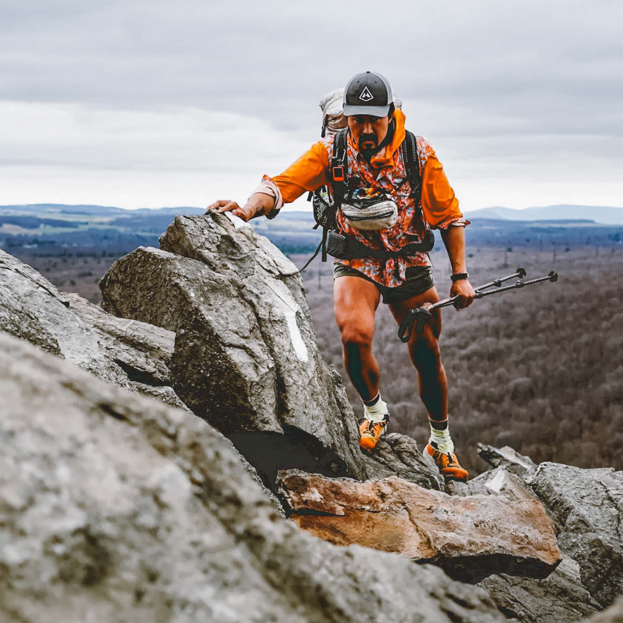 A man hiking up a mountain with a backpack and poles.