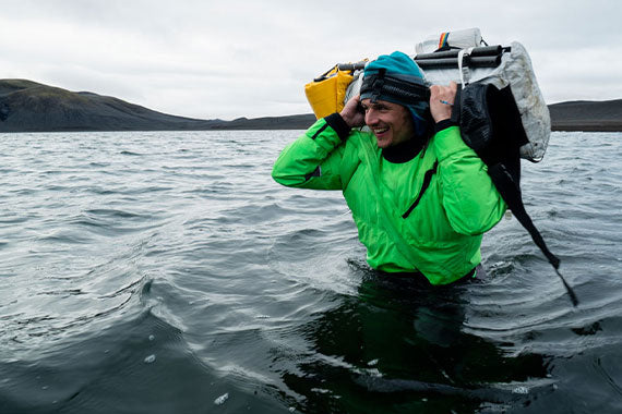 A man carrying a backpack in the water.