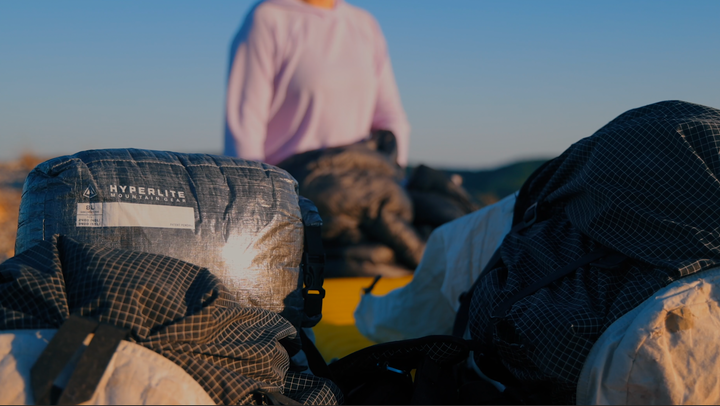 A woman is standing on top of a backpack.