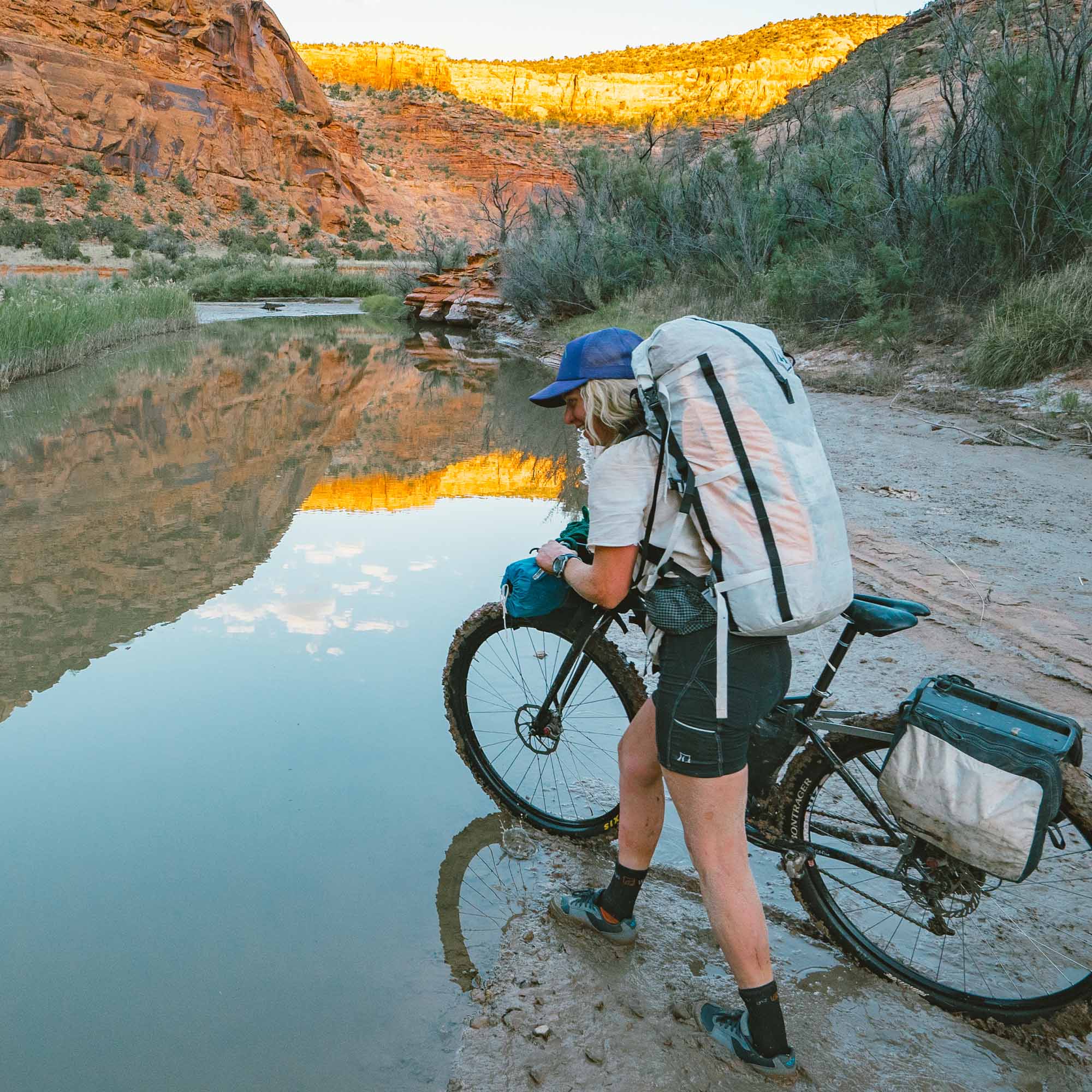 A woman riding a bike near a river.