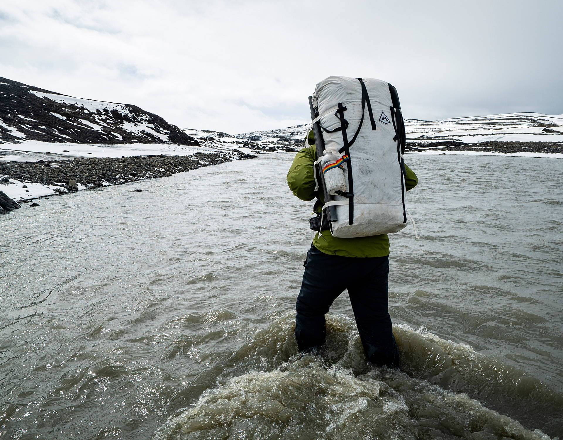 A man carrying a large backpack in the water.